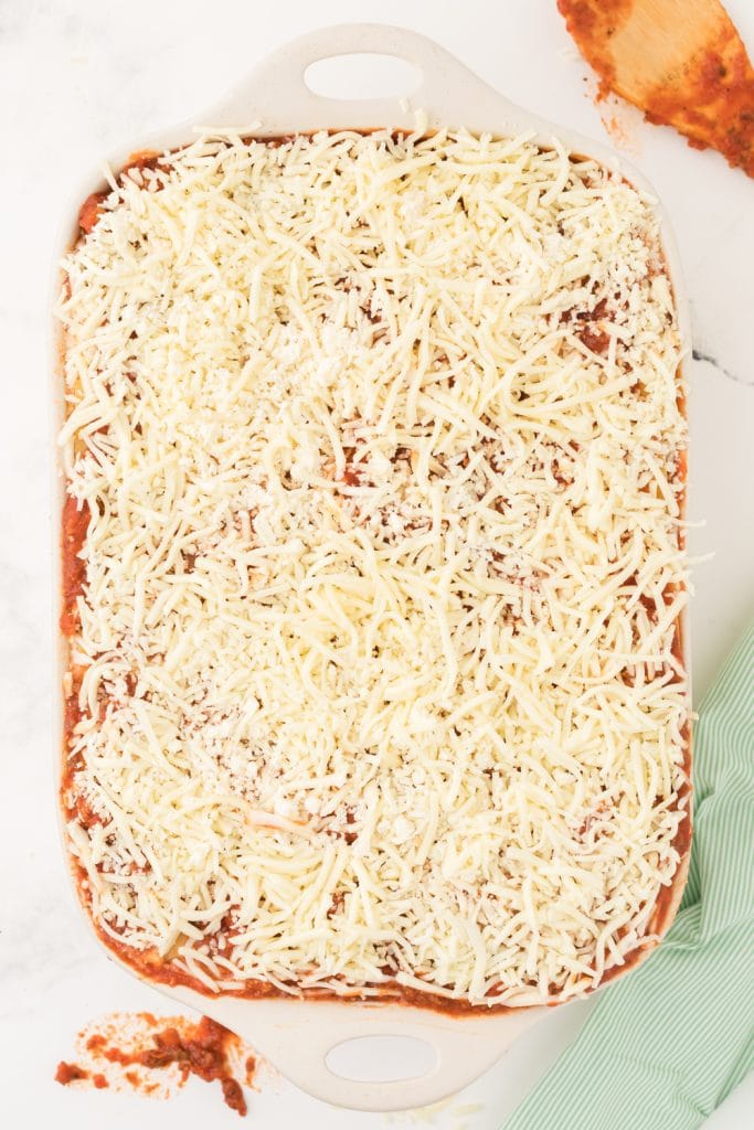 fully layered lasagan in a big white pan with lots of cheese on top