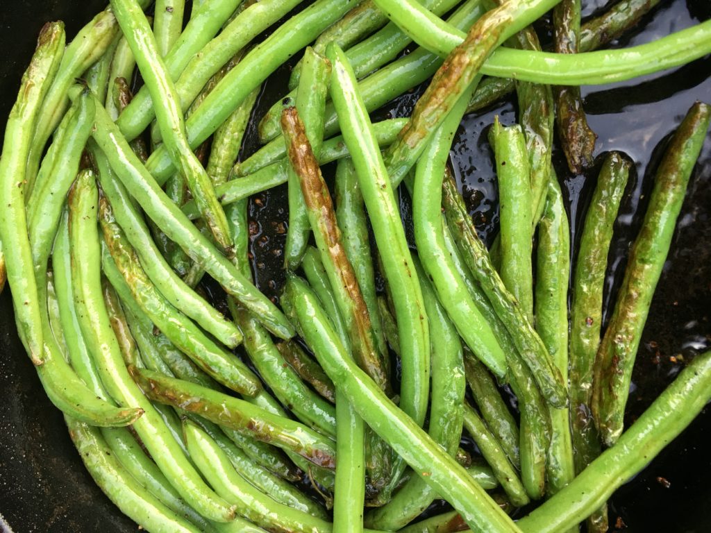 blistered green beans in a skillet