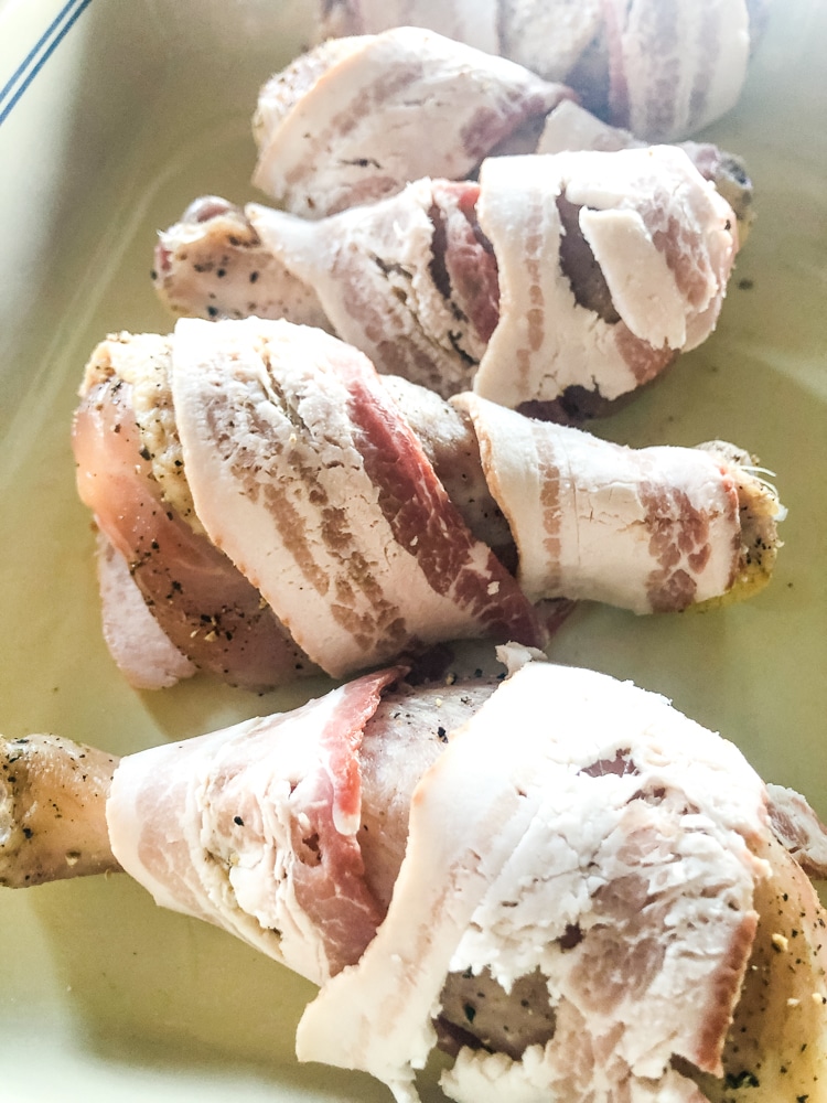 bacon wrapped drumsticks in a baking dish