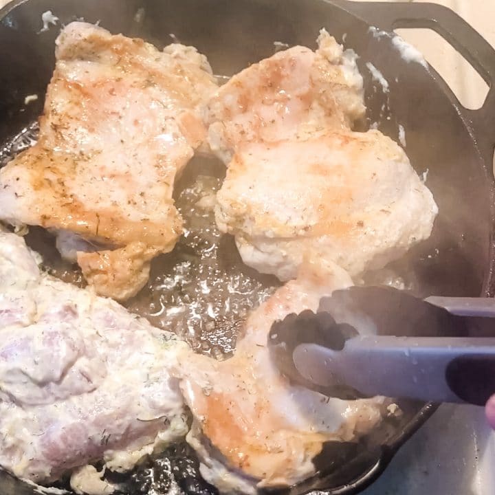 flipping chicken thighs over in a skillet