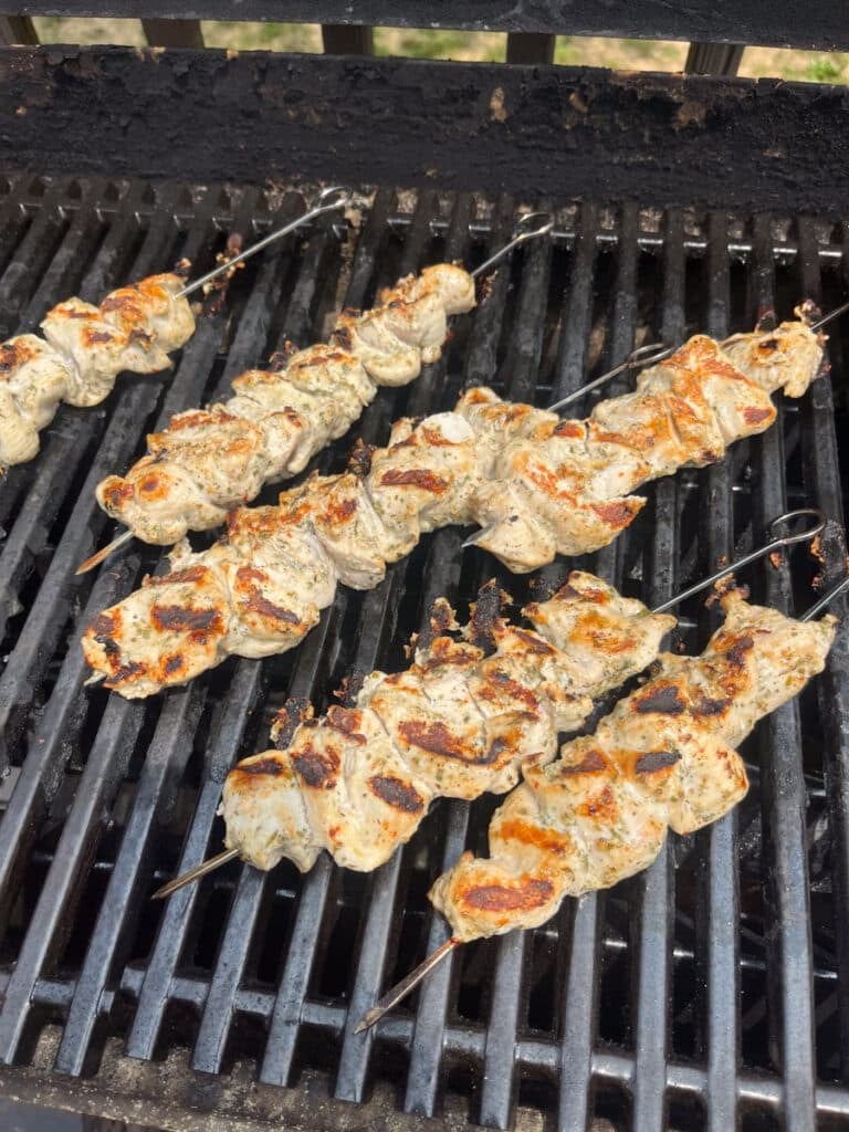 grilling greek chicken skewers outside