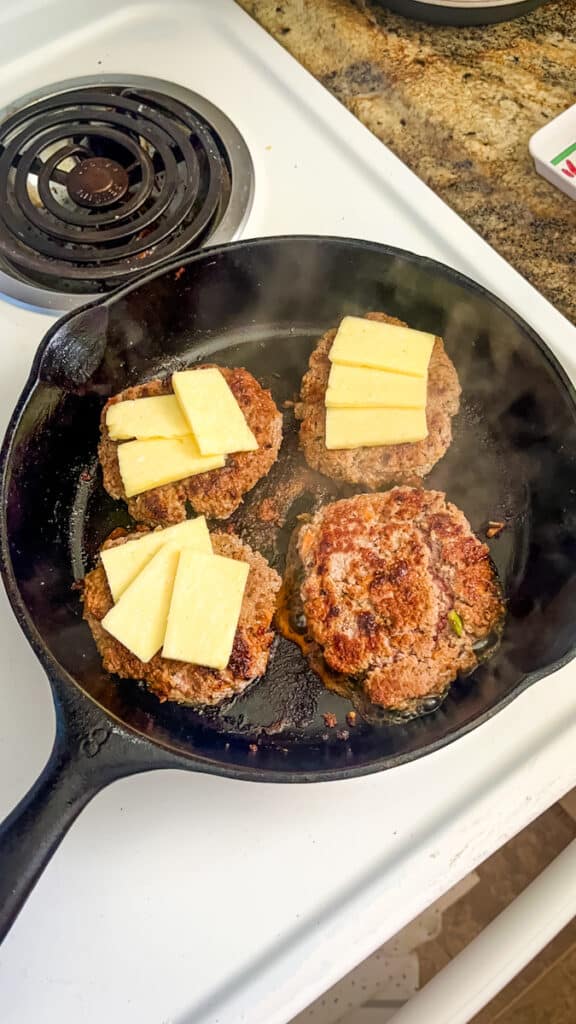 adding cheese to stovetop burgers
