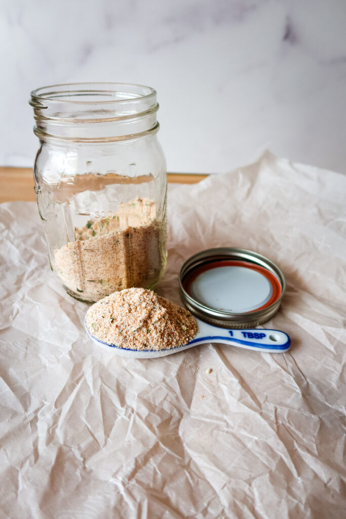 Jar of Firecracker Seasoning surrounded by garlic powder, onion powder, and chives.