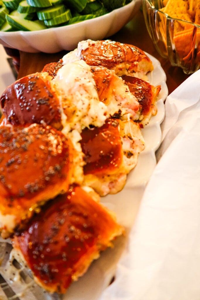 Swiss onion ham sliders served on a game day appetizer table with chips and dip.
