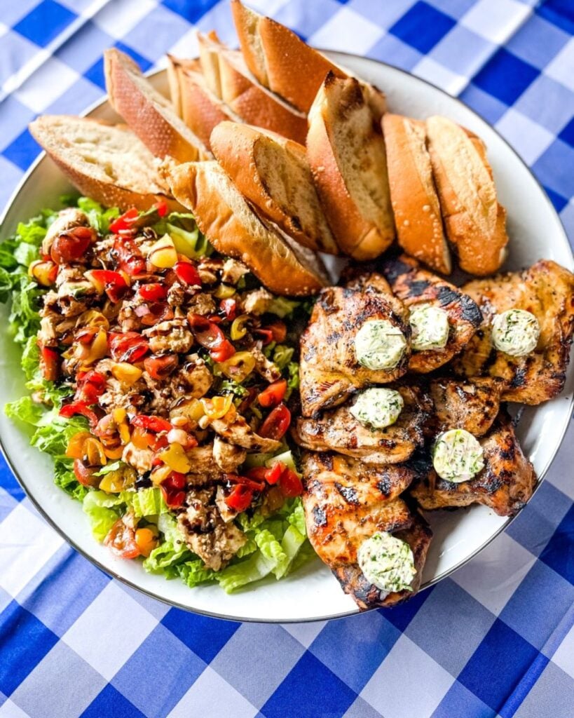 Grilled chicken breast plated with a Caprese Caesar salad topped with mozzarella and tomatoes