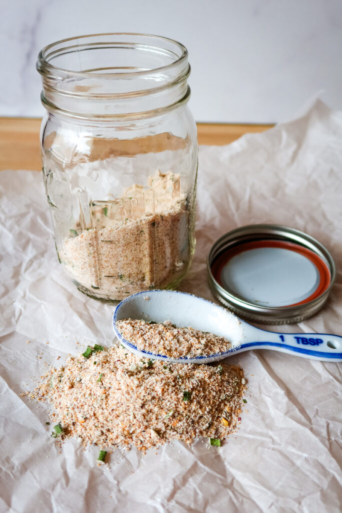 Close-up of Sweetpea Firecracker Seasoning Blend in a glass jar on a white background.