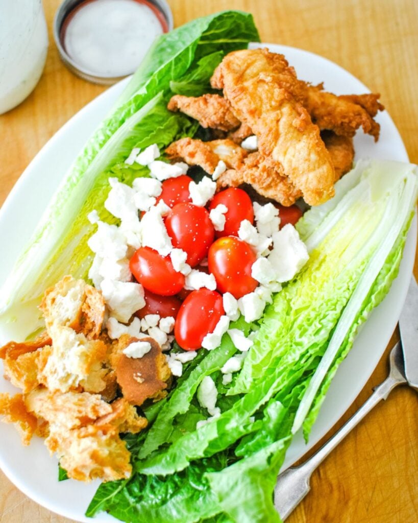 Crisp wedge salad topped with bacon, dressing, and crispy chicken tenders