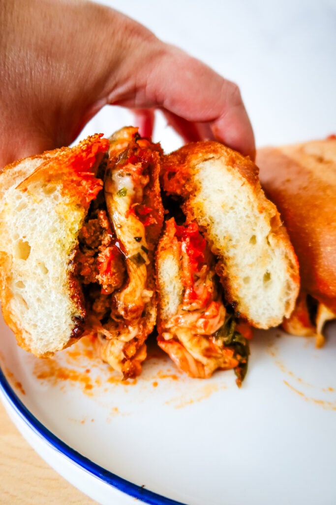 Cut smashed meatball sub showing melty mozzarella, marinara, and garlic bread.