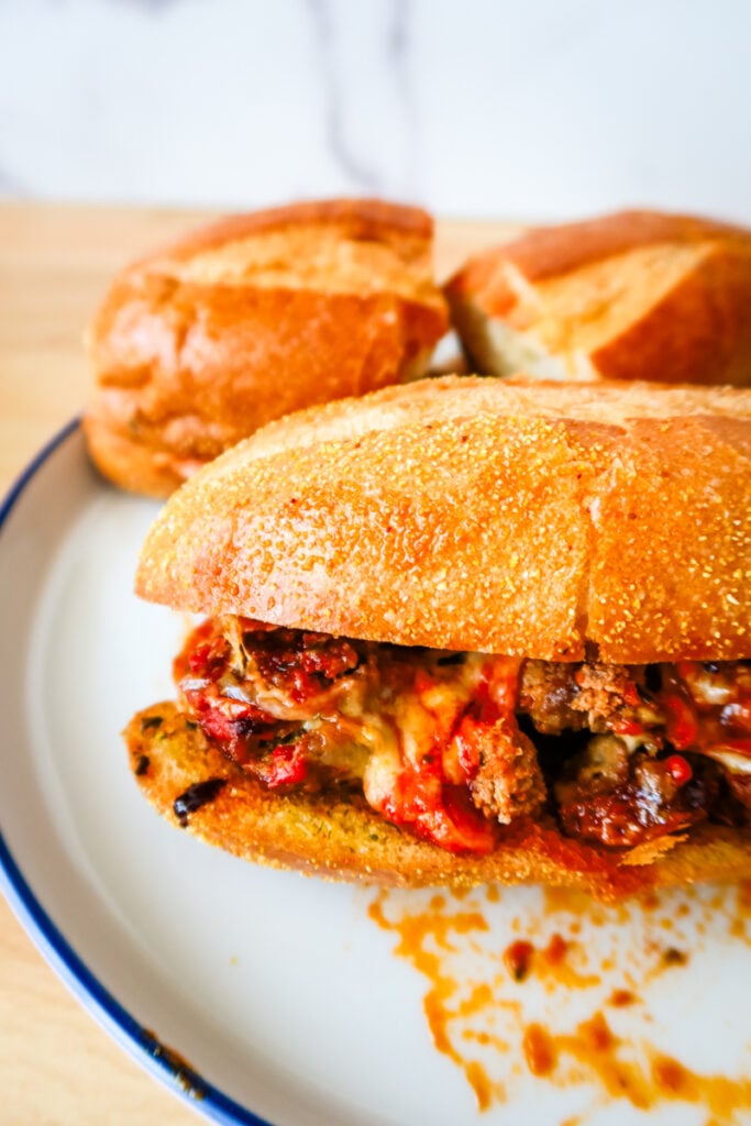 Smashed meatball sub with gooey mozzarella and marinara sauce spilling onto plate.