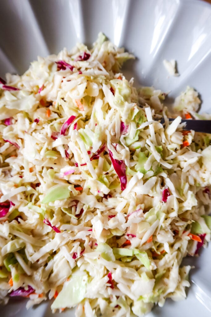 Close-up of creamy coleslaw with shredded cabbage, carrots, and red cabbage mixed together.