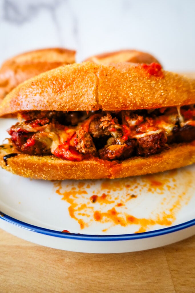 Close-up of smashed meatball sub on toasted garlic bread with marinara and mozzarella.