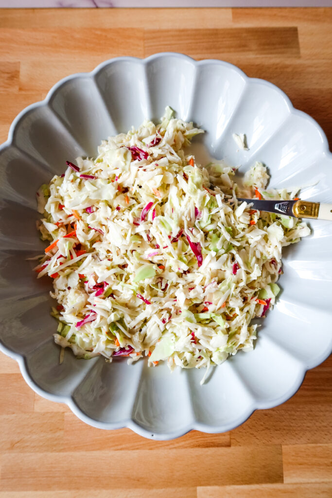 Overhead view of a large white serving dish filled with creamy homemade coleslaw.