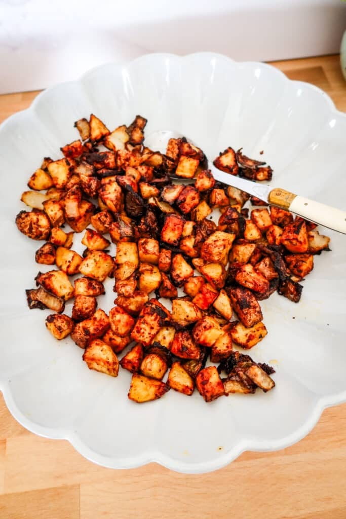 Crispy diced potatoes and onions tossed with Firecracker seasoning, piled high in a scalloped white dish.