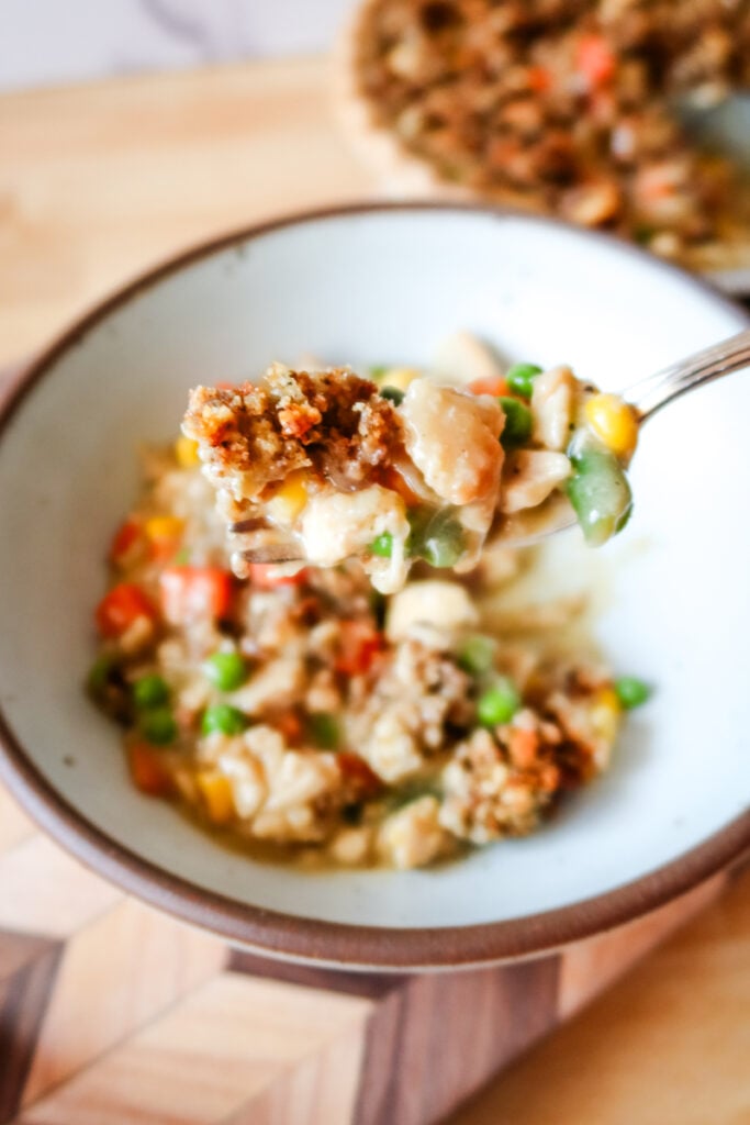 forkful of creamy chicken pot pie with vegetables and crispy stuffing topping