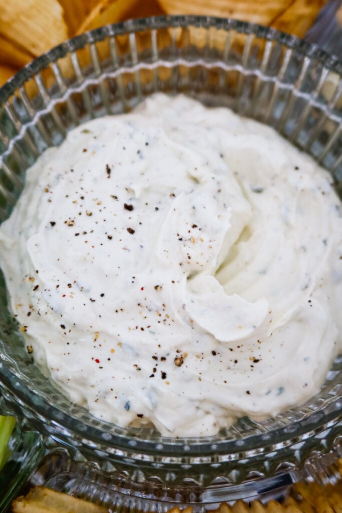 Close-up view of thick, creamy homemade ranch dip topped with cracked black pepper in a glass bowl.