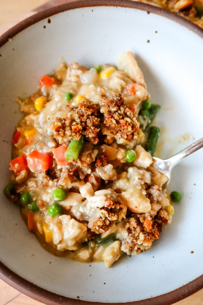 close-up view of a bowl filled with creamy chicken pot pie filling and stuffing topping