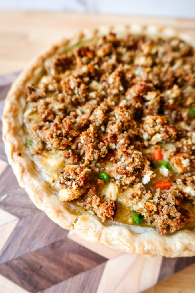 side angle of baked chicken pot pie showing flaky crust and crispy stuffing topping