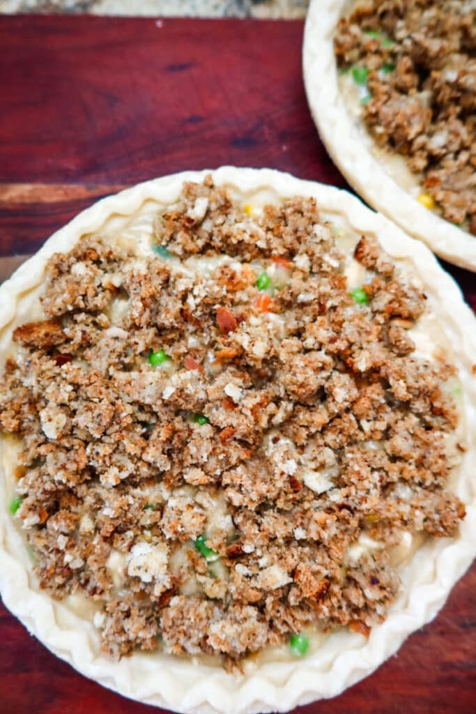 close up overhead view of chicken pot pie filled with chicken and vegetables and topped with stuffing before baking