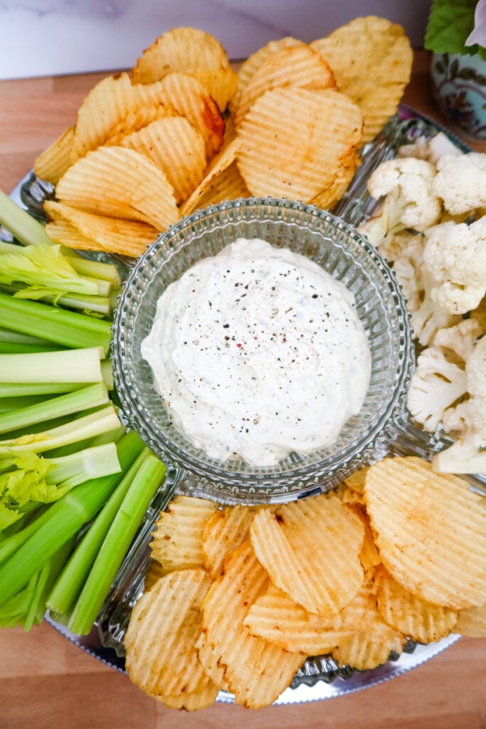 A bowl of creamy homemade ranch dip surrounded by fresh vegetables and chips on a cozy table — the perfect game day or meal prep recipe.