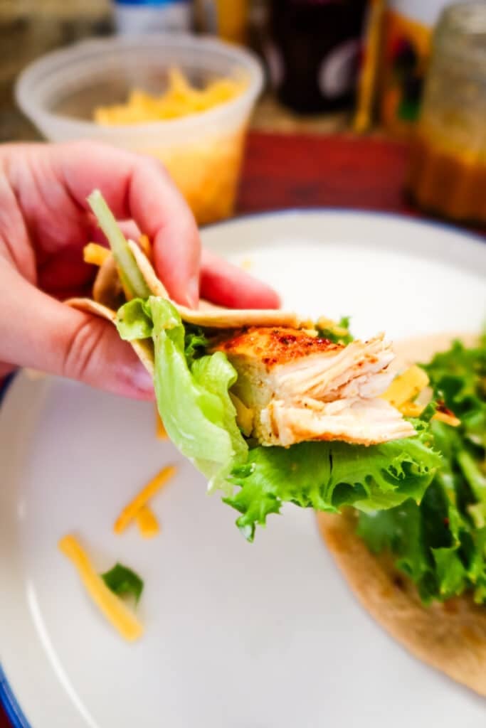 Hand holding a chicken snack wrap filled with lettuce, cheddar, and juicy air fryer chicken.