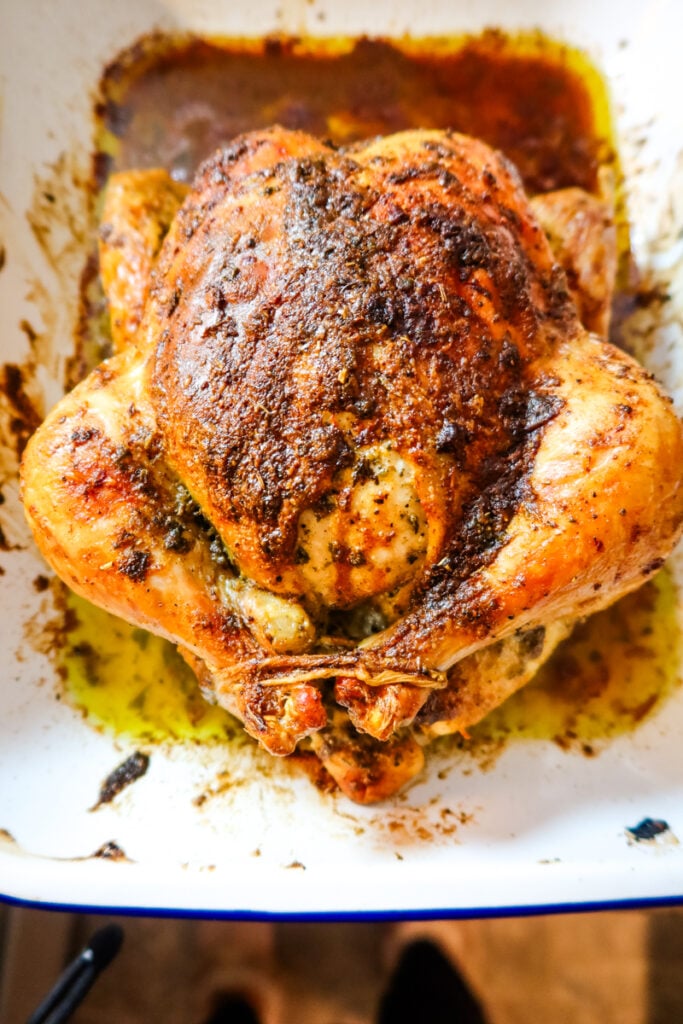 Whole roasted chicken resting in pan juices, coated with Thanksgiving Butternaise for crispy, seasoned skin.