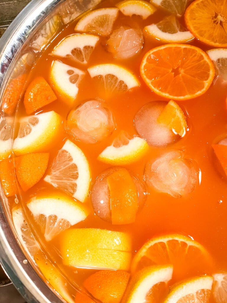 Close-up of orange and lemon slices floating in Jingle Juice Christmas punch with ice