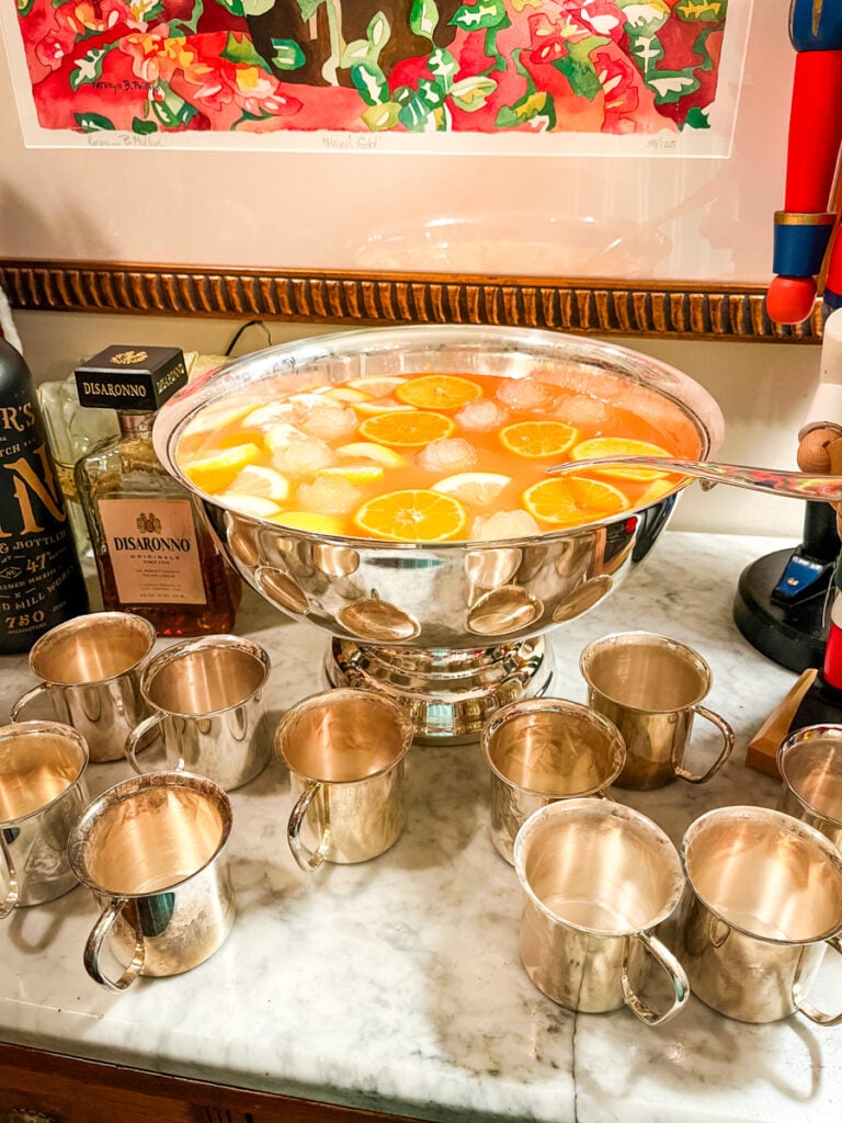 Holiday drink station with Jingle Juice punch, nutcrackers, shrimp cocktails, and silver serving cups