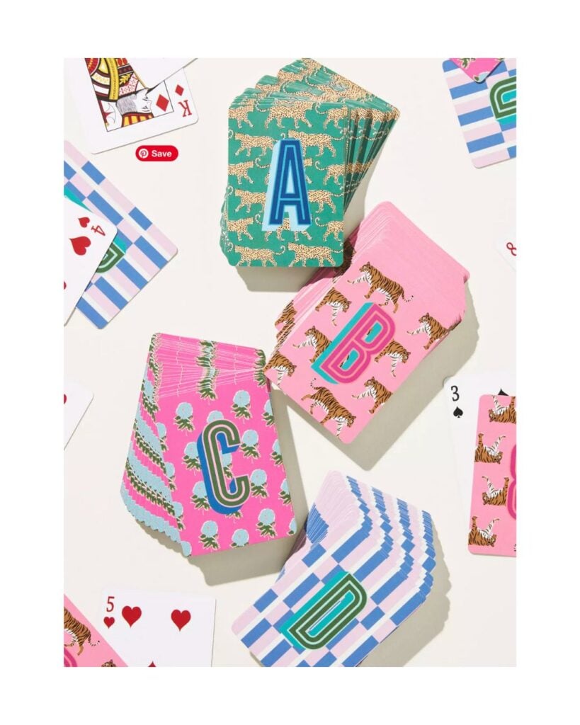 Monogrammed playing cards with colorful patterns spread across a table