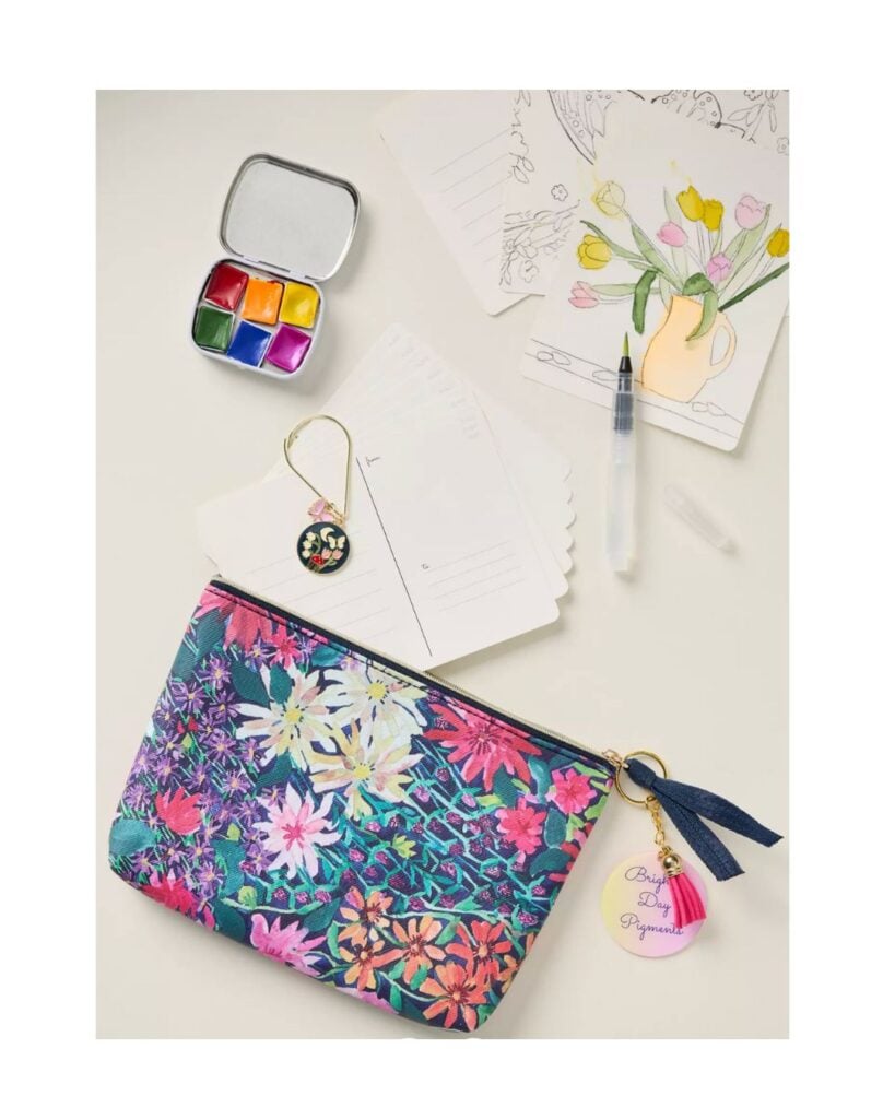 Small travel watercolor paint set with brush, postcards, and painted illustration