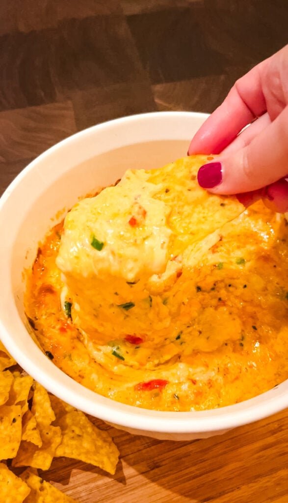 close up scoop of creamy baked pimento cheese dip on tortilla chip