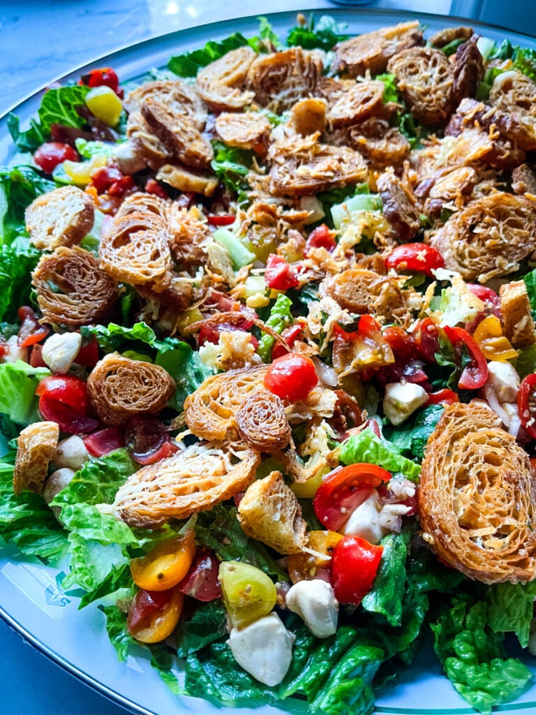 Caprese Caesar salad with crispy toppings, tomatoes, and greens in large serving bowl