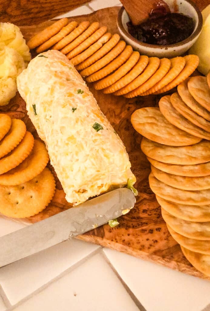 Close-up of a Green Onion Cheeseball appetizer served with buttery crackers on a charcuterie-style snack board for easy entertaining.