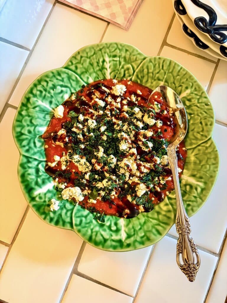 Boursin Marinara Dip with red marinara sauce, crumbled herbed cheese, fresh herbs, and balsamic glaze served in a green cabbage-shaped bowl.