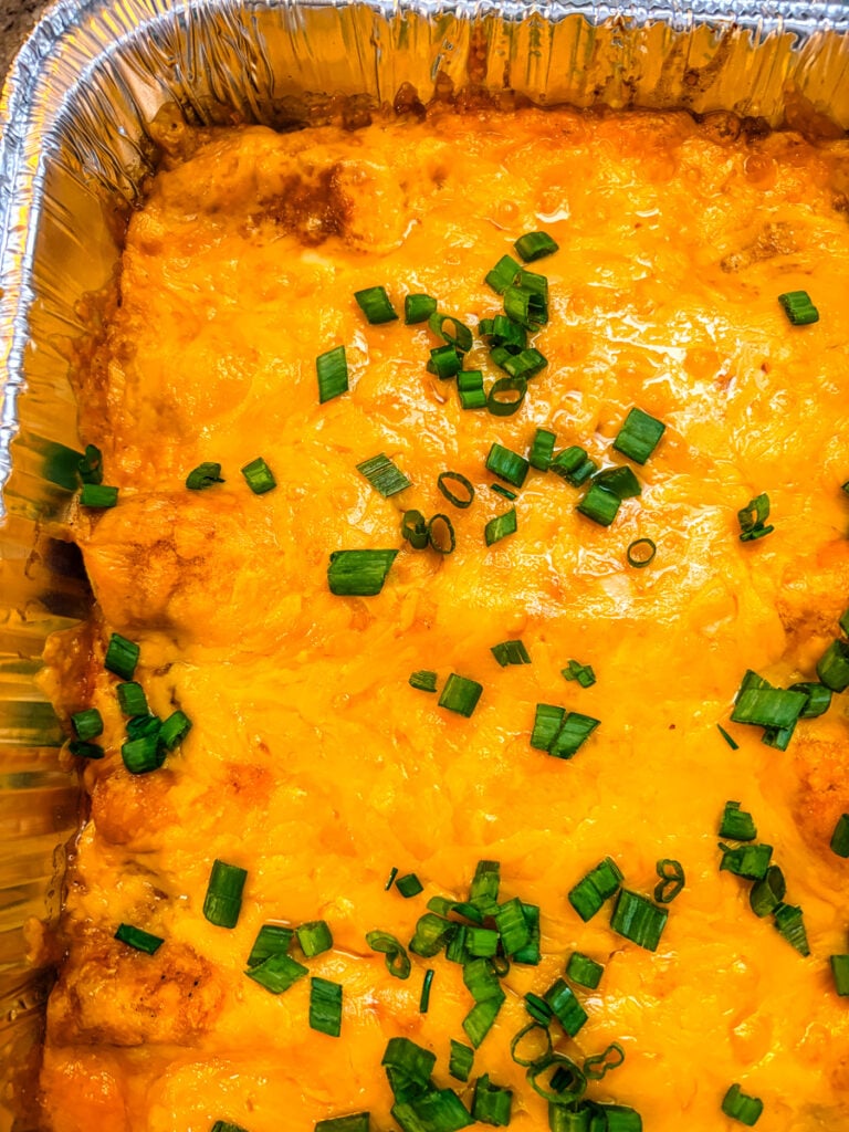 Hands filling a large flour tortilla with creamy pulled pork and white bean mixture before rolling it into an enchilada.
